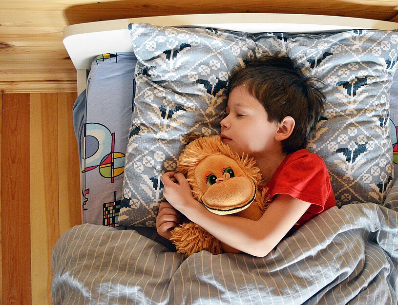 Schlafendes Kind im Bett mit Kuscheltier