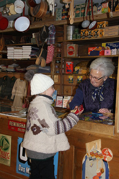 Ein Mädchen kauft Süßigkeiten in einer Greisslerei.