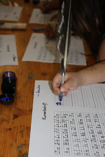 Ein Kind schreibt mit einer Schreibfeder.
