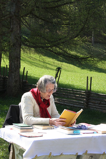 Eine Dame liest aus einem Buch im Freien.