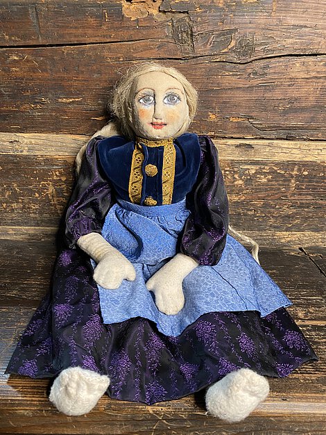 Eine Puppe im blauen Kleid.