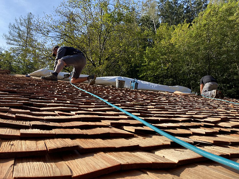 Dacherneuerung an einem Schindeldach durch Bauarbeiter