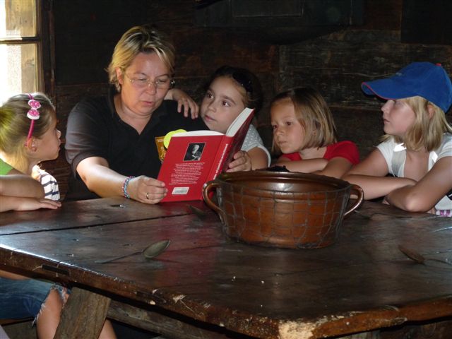 Eine Dame liest Kindern aus einem Buch vor.